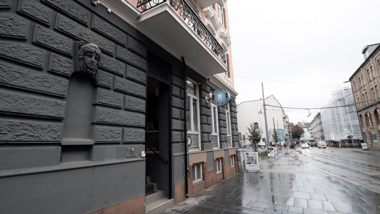 Utendørsbilde av tannlegeklinikken Dental Park i en klassisk bygård med grå murvegg. Skiltet markerer inngangen fra gatenivå i krysset mellom Hegdehaugsveien og Parkveien.